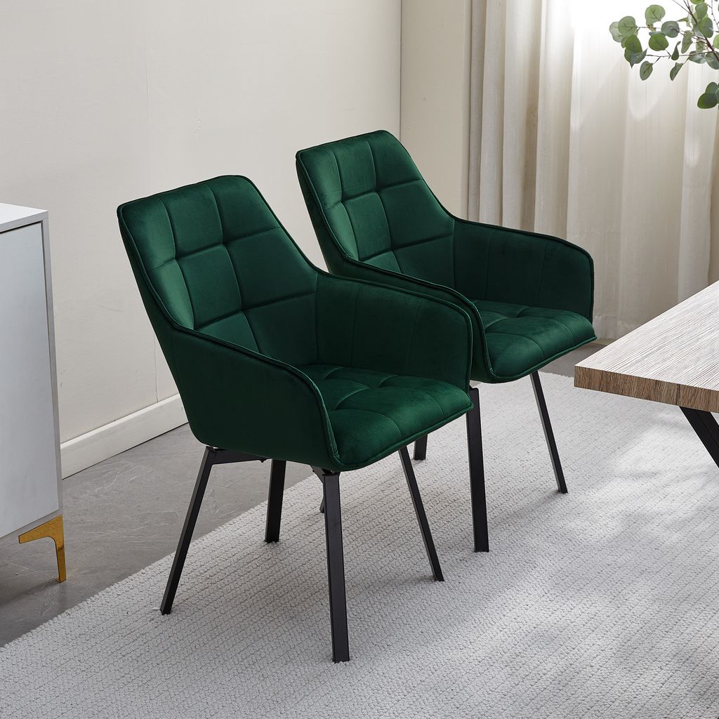 Two green velvet dining chairs are shown in a room with a light-colored rug and a table.