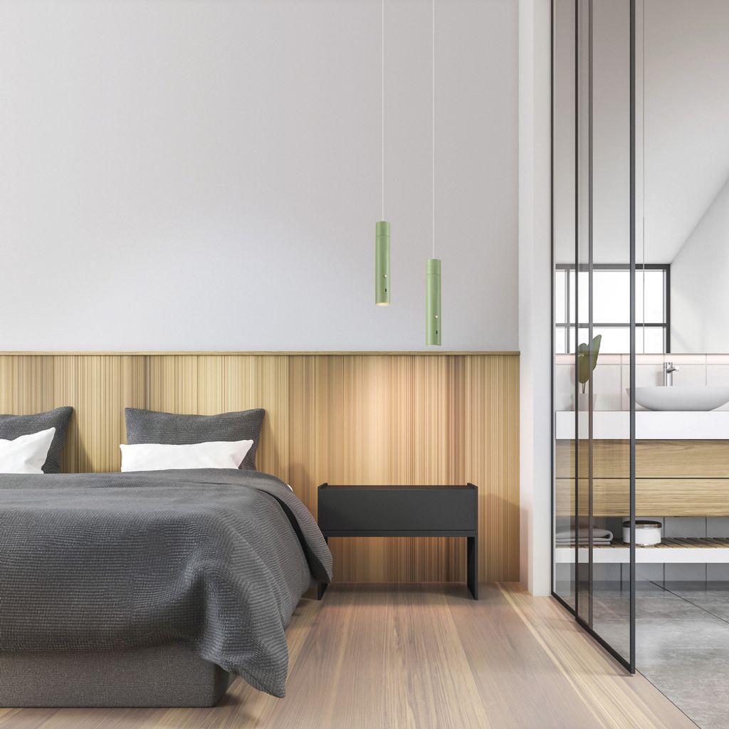 A modern bedroom with a bed, bedside table, and a glimpse of a bathroom through a glass partition.