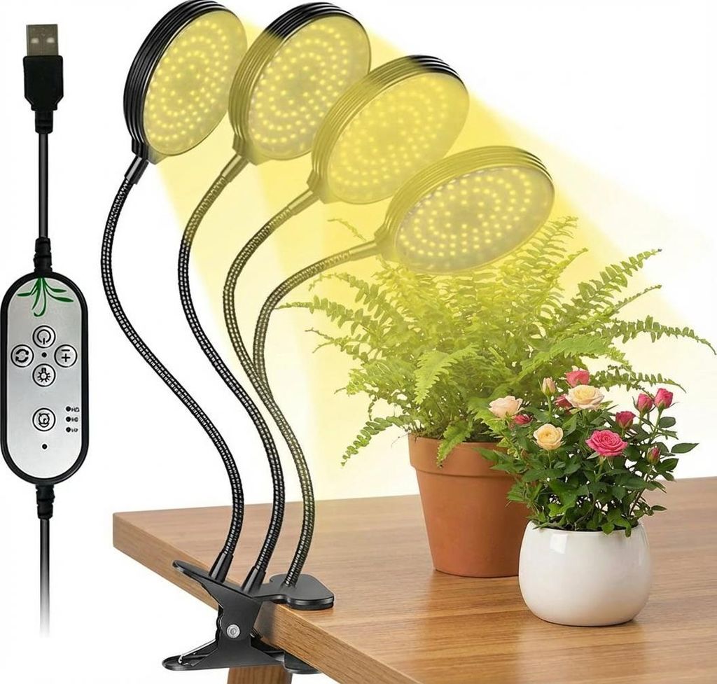 A clip-on LED grow light illuminating two potted plants on a wooden desk.