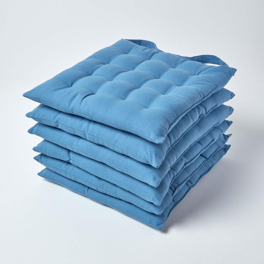 A stack of blue seat cushions on a white background.