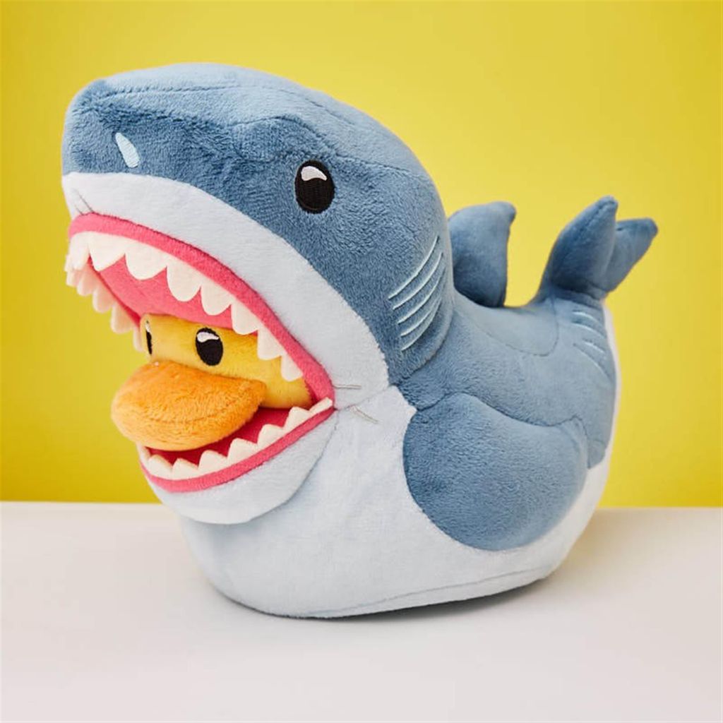 A plush toy shark with its mouth open, revealing a plush toy duck inside.