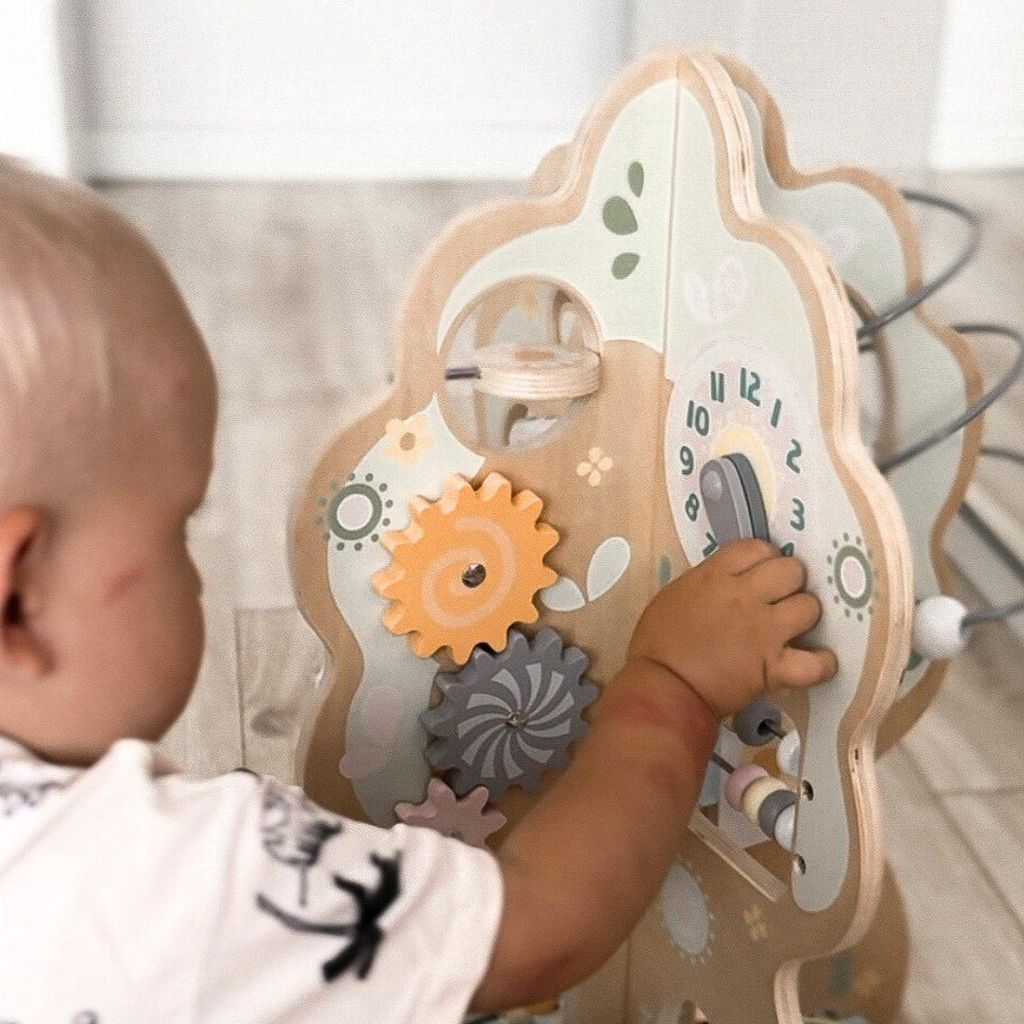 A baby is playing with a wooden activity tree toy.