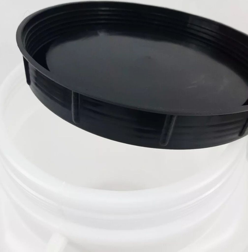 A close-up view of a black lid resting on the rim of a white container.