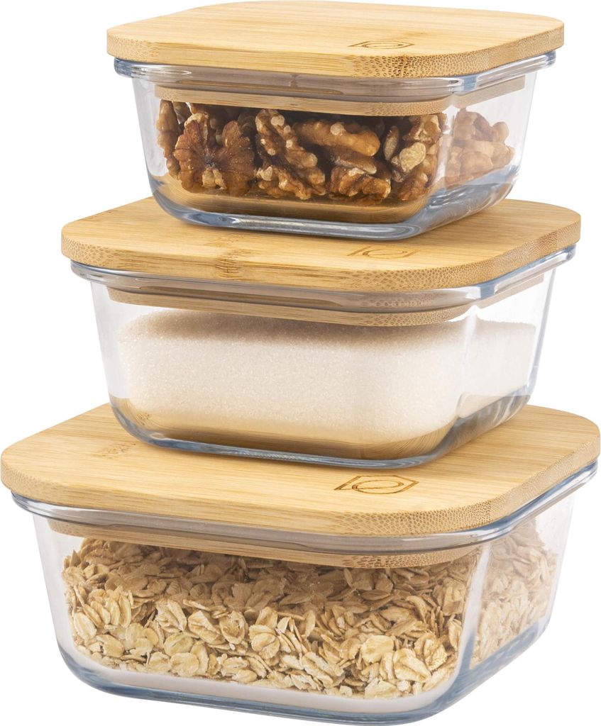 Three glass storage containers with bamboo lids are stacked on top of each other. The top container holds walnuts, the middle container holds sugar, and the bottom container holds oats.