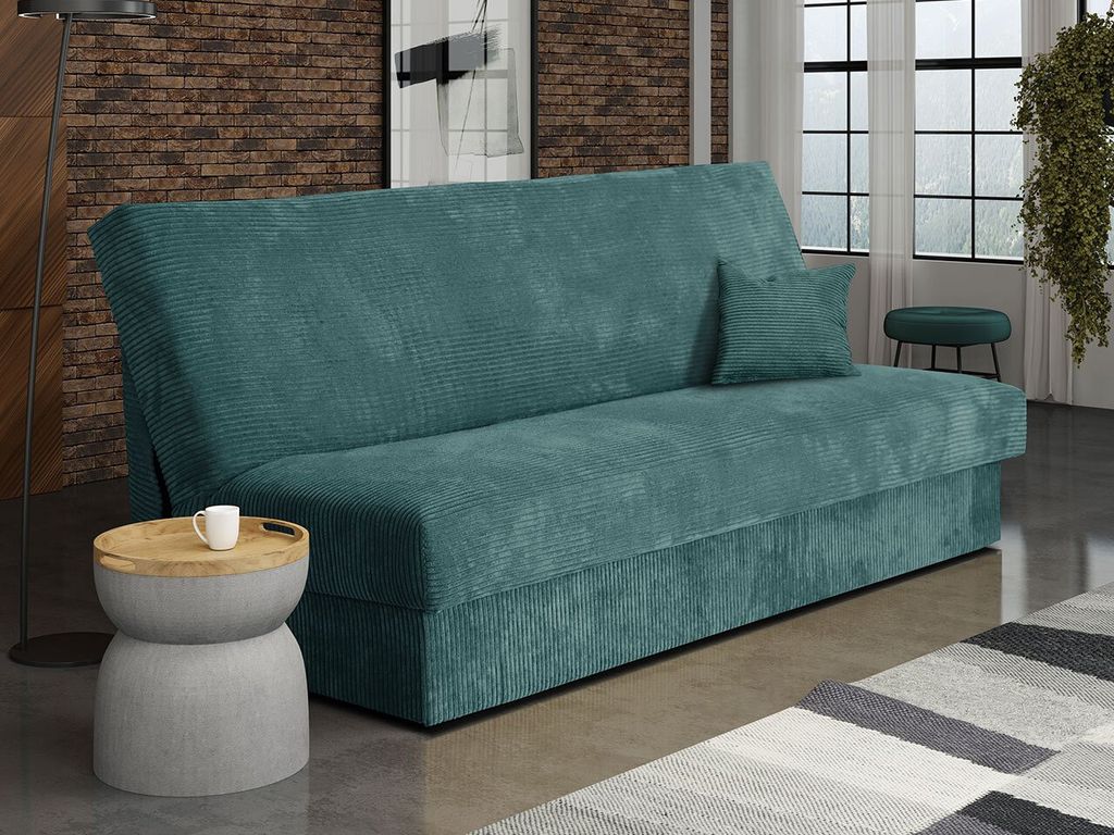 A teal corduroy sofa bed is shown in a living room setting with a small side table and a rug.