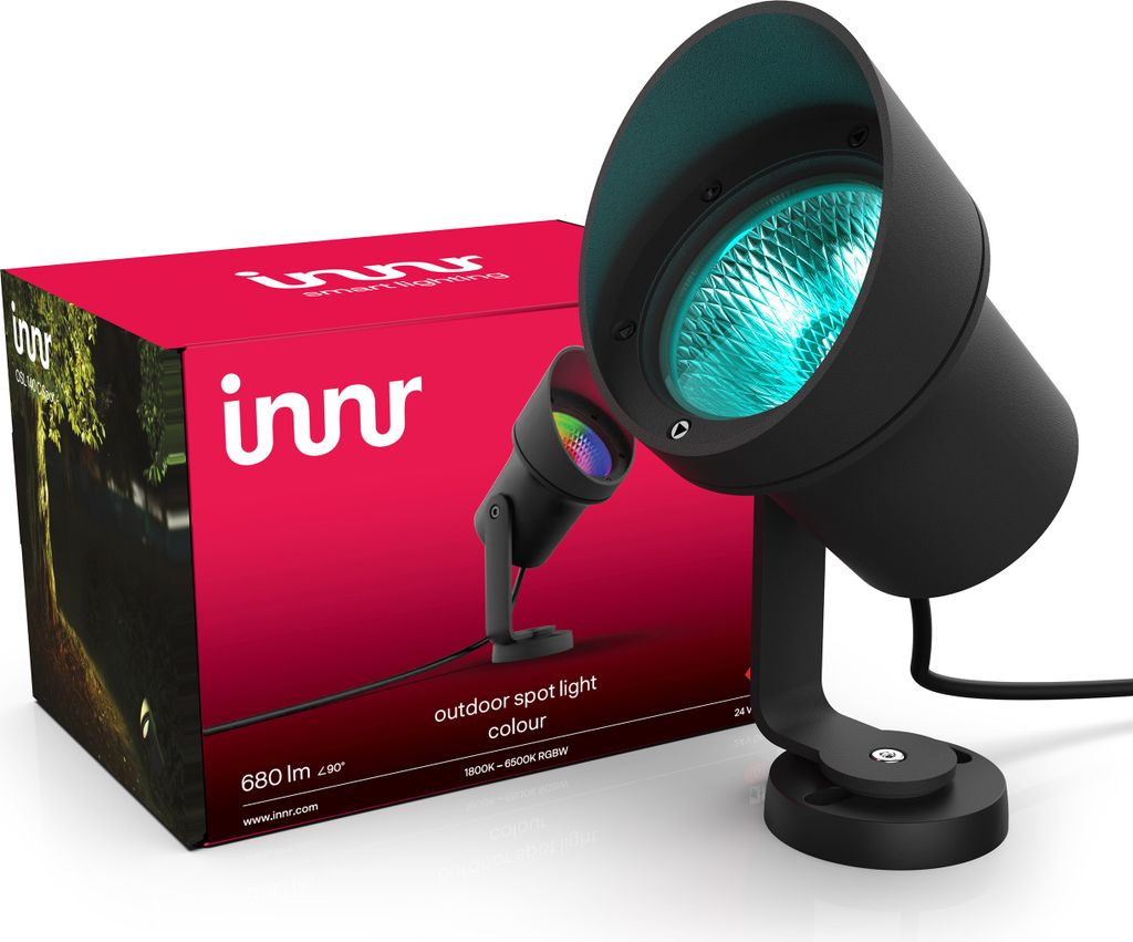 A product box for an Innr outdoor spotlight is shown next to the spotlight itself. The spotlight is black and emits a blue light. The box is red and features the Innr logo and an image of a garden path at night.