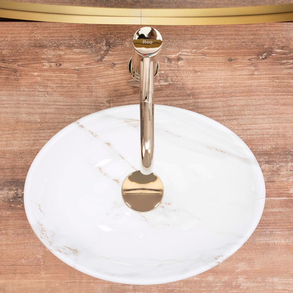 A top-down view of a marble sink with a gold faucet.