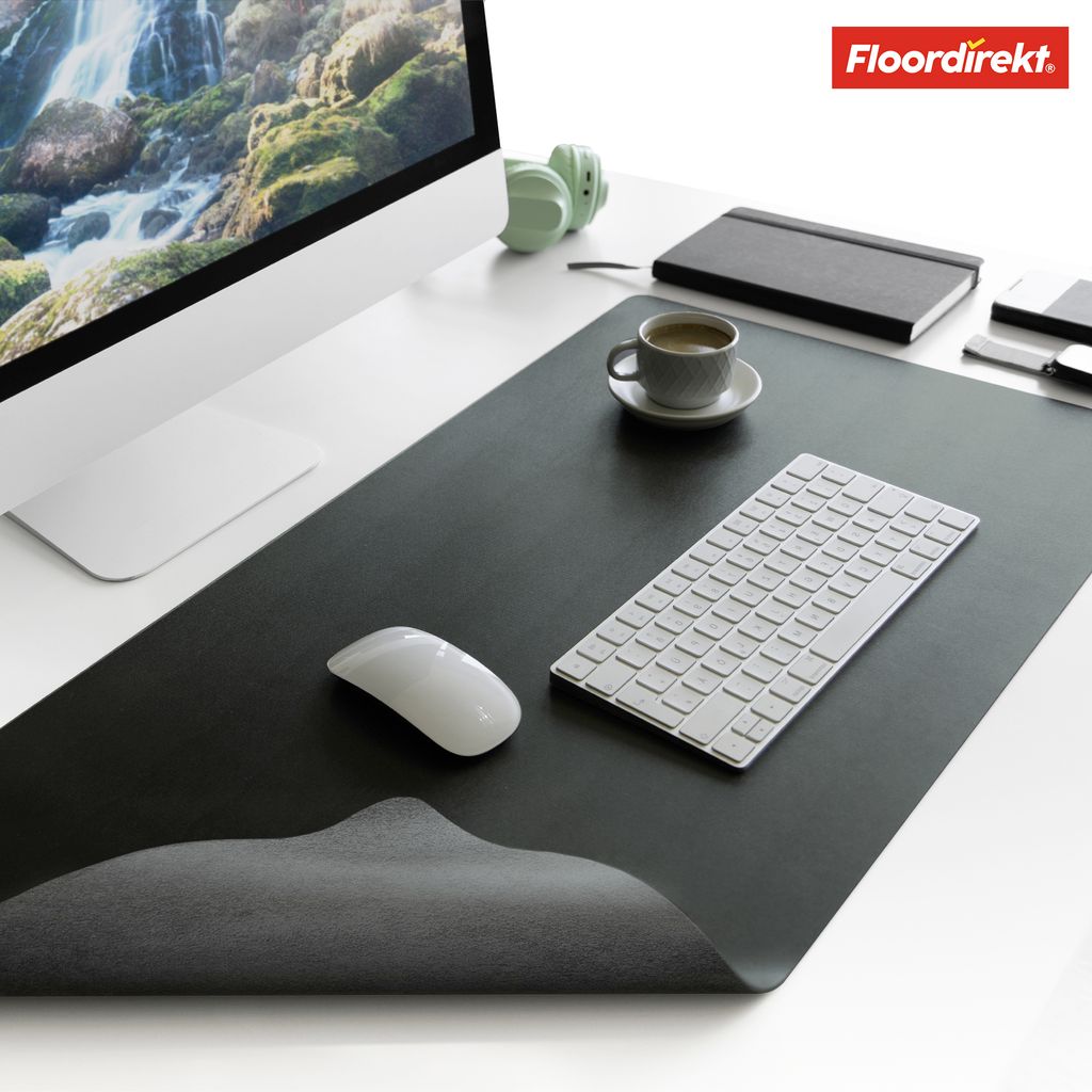 A desk setup with a computer monitor, keyboard, mouse, headphones, and a cup of coffee on a large desk mat.
