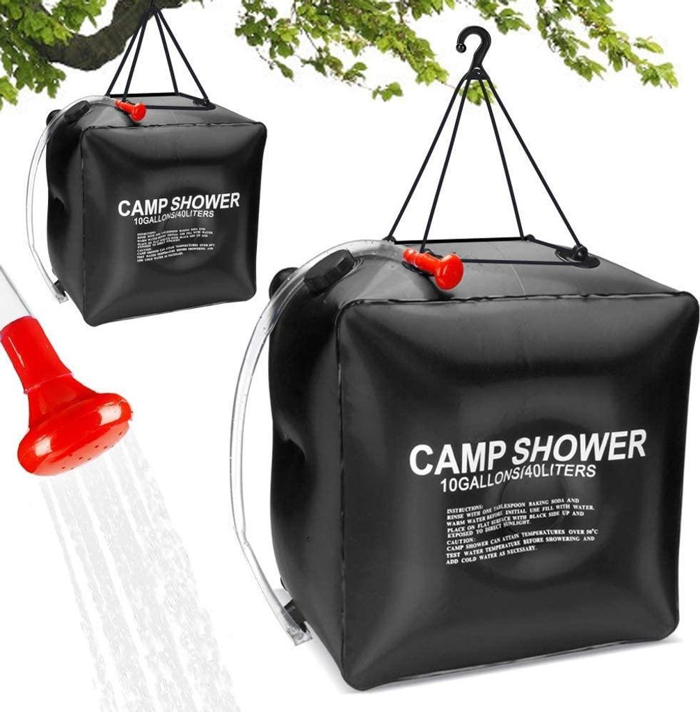 A black solar shower bag is hanging from a tree branch, with a red shower head spraying water.
