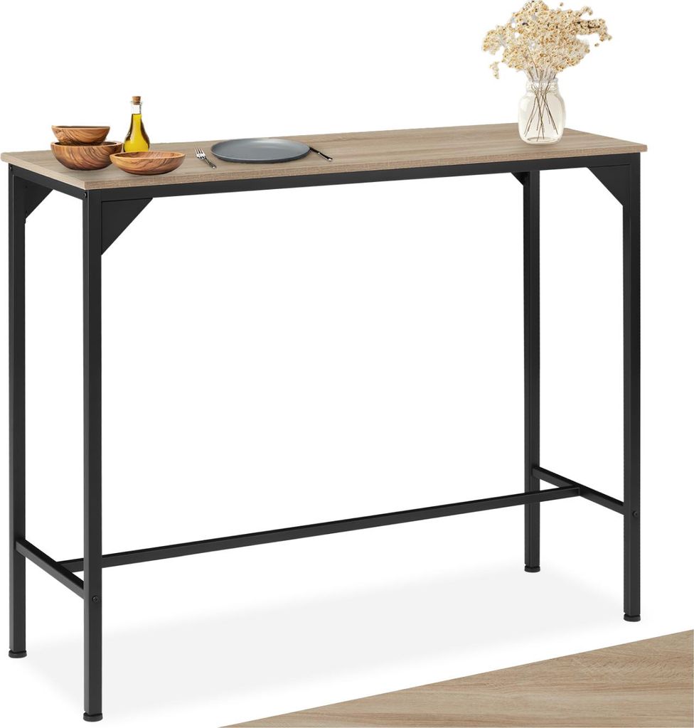 A bar table with a wooden top and black metal legs, set against a white background. Decorative items like bowls, a bottle, and a vase with dried flowers are placed on the table.
