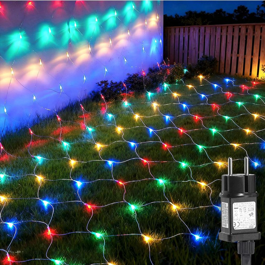 A net of colorful LED lights is spread across a grassy lawn and draped over a wall at night.