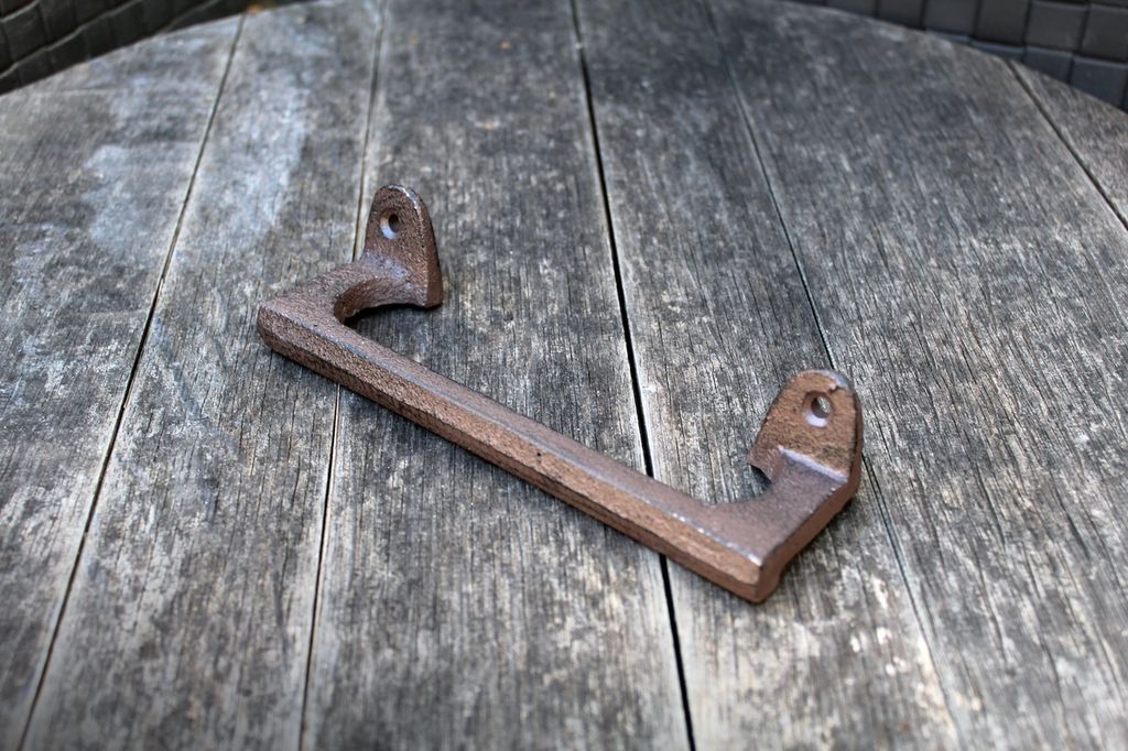 A cast iron handle resting on a wooden surface.
