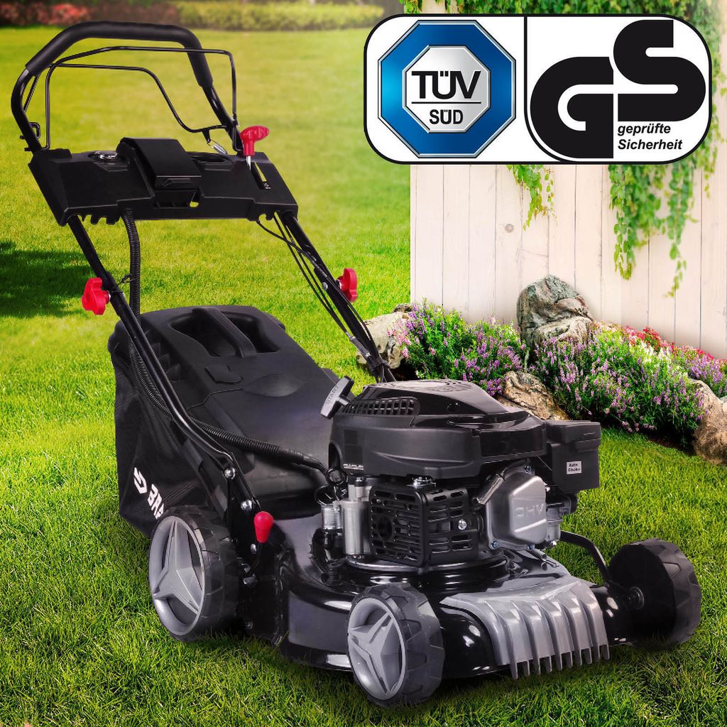 A lawnmower is shown on a grassy lawn with some bushes and a white fence in the background. There are also certification logos in the top right corner.