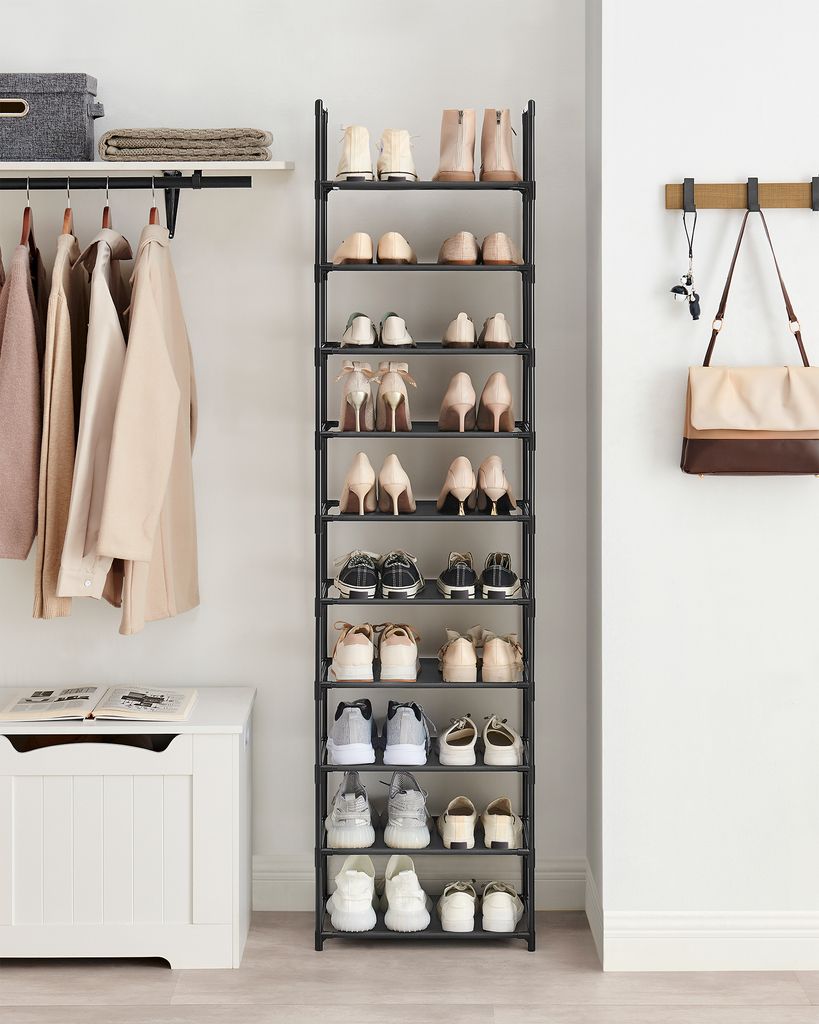 A tidy entryway with a shoe rack, coats on a hanging rack, and a storage bench.