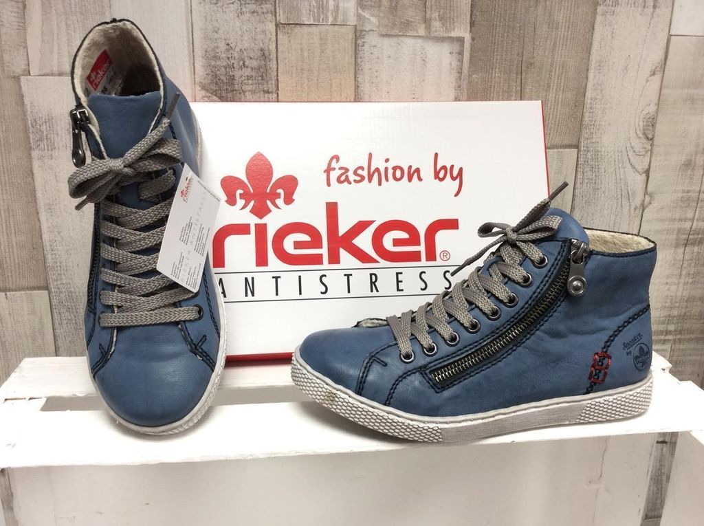 A pair of blue Rieker lace-up boots are displayed next to their branded box.