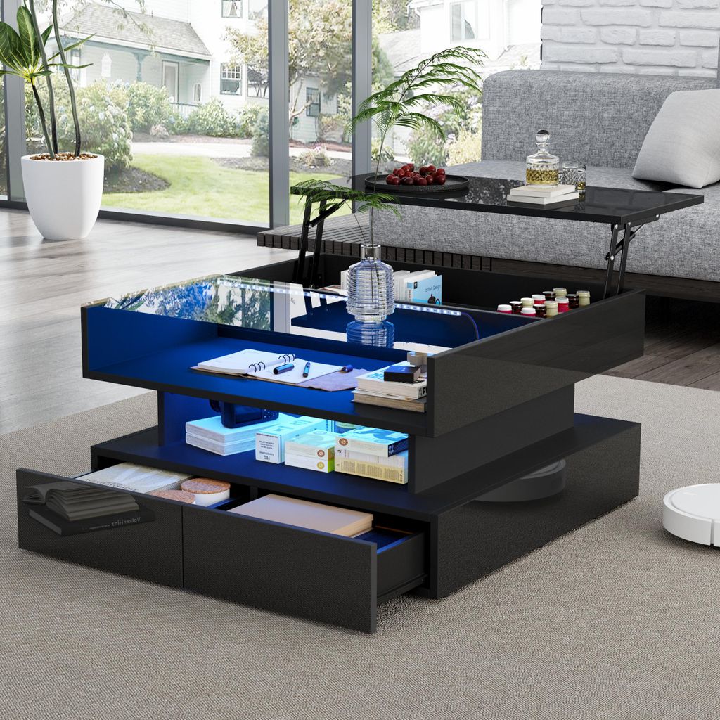 A modern living room with a black hydraulic coffee table with LED lighting, a sofa, and a large window overlooking a garden.