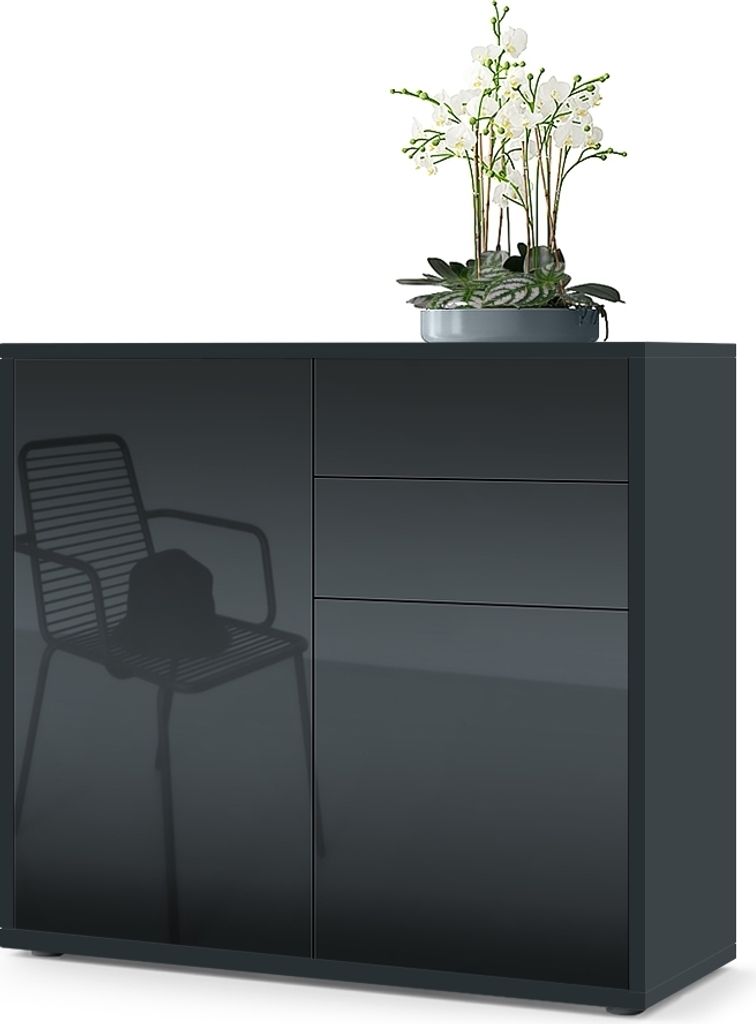 A dark gray sideboard with a reflection of a chair and hat on the left door, and three drawers on the right. A potted plant with white flowers sits on top.