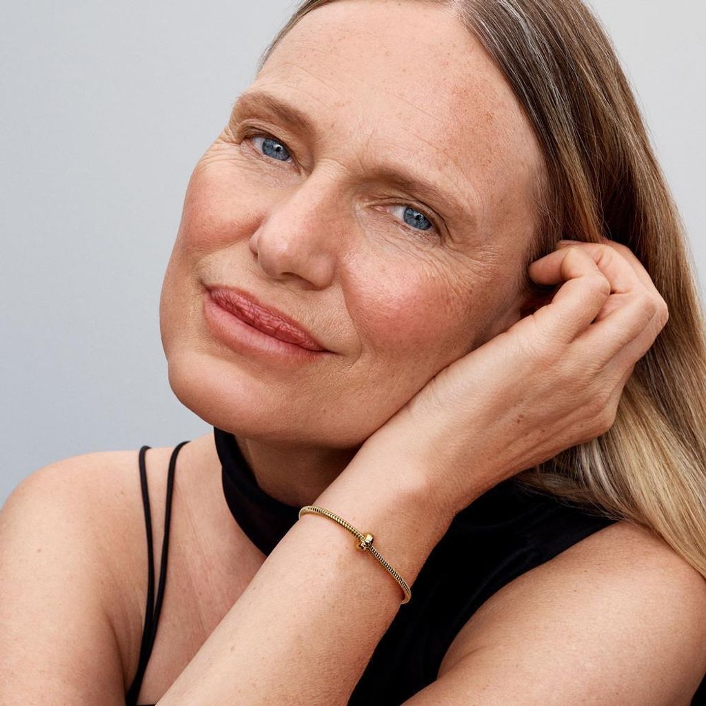 Close-up of a woman's face and arm, wearing a bracelet.