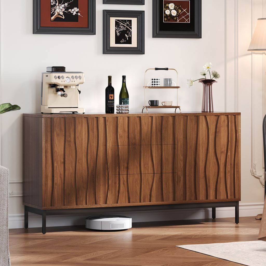 A wooden sideboard with decorative carvings is shown in a room, with a coffee machine, wine bottles, and decorative items on top. A robot vacuum cleaner is on the floor underneath.