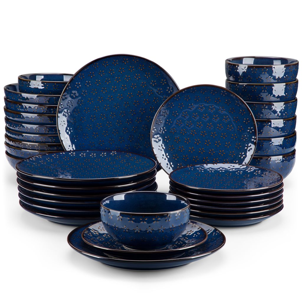 A set of blue ceramic dishes with a floral pattern and gold trim, arranged in stacks and piles against a white background.