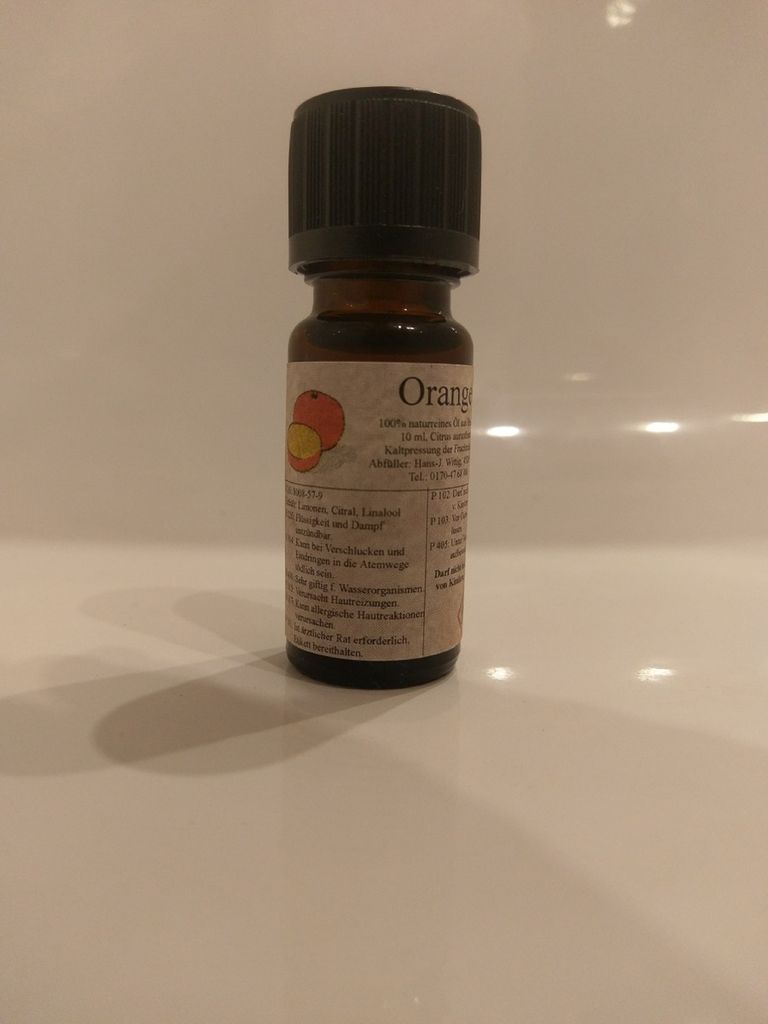 Kleine braune Flasche mit einem schwarzen Verschluss. Auf dem Etikett steht "Orange".