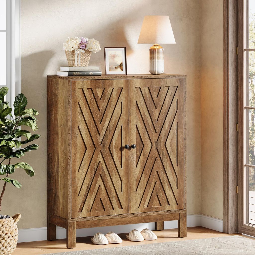 A wooden cabinet with a geometric pattern on the doors, placed in a room with a lamp, books, and a plant.