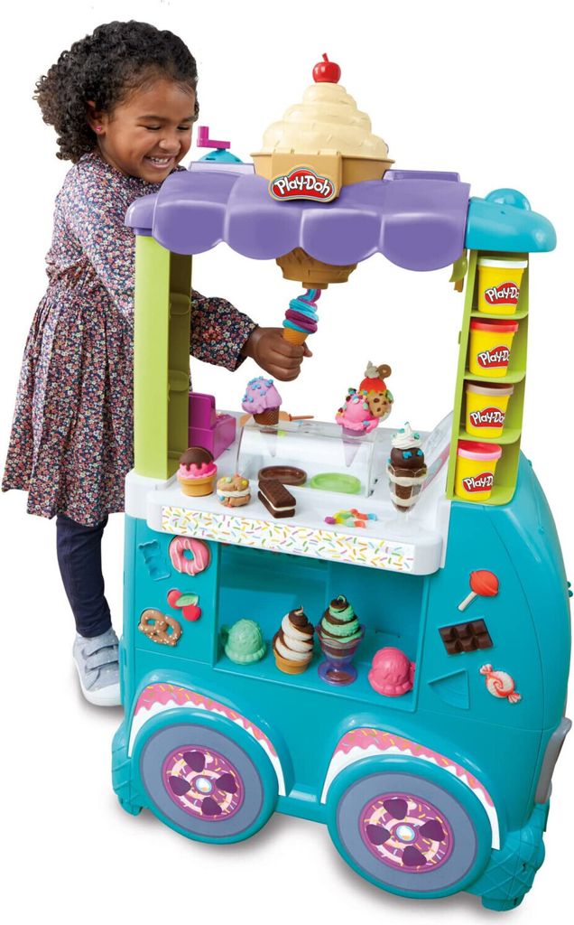 A young girl is playing with a Play-Doh ice cream cart.