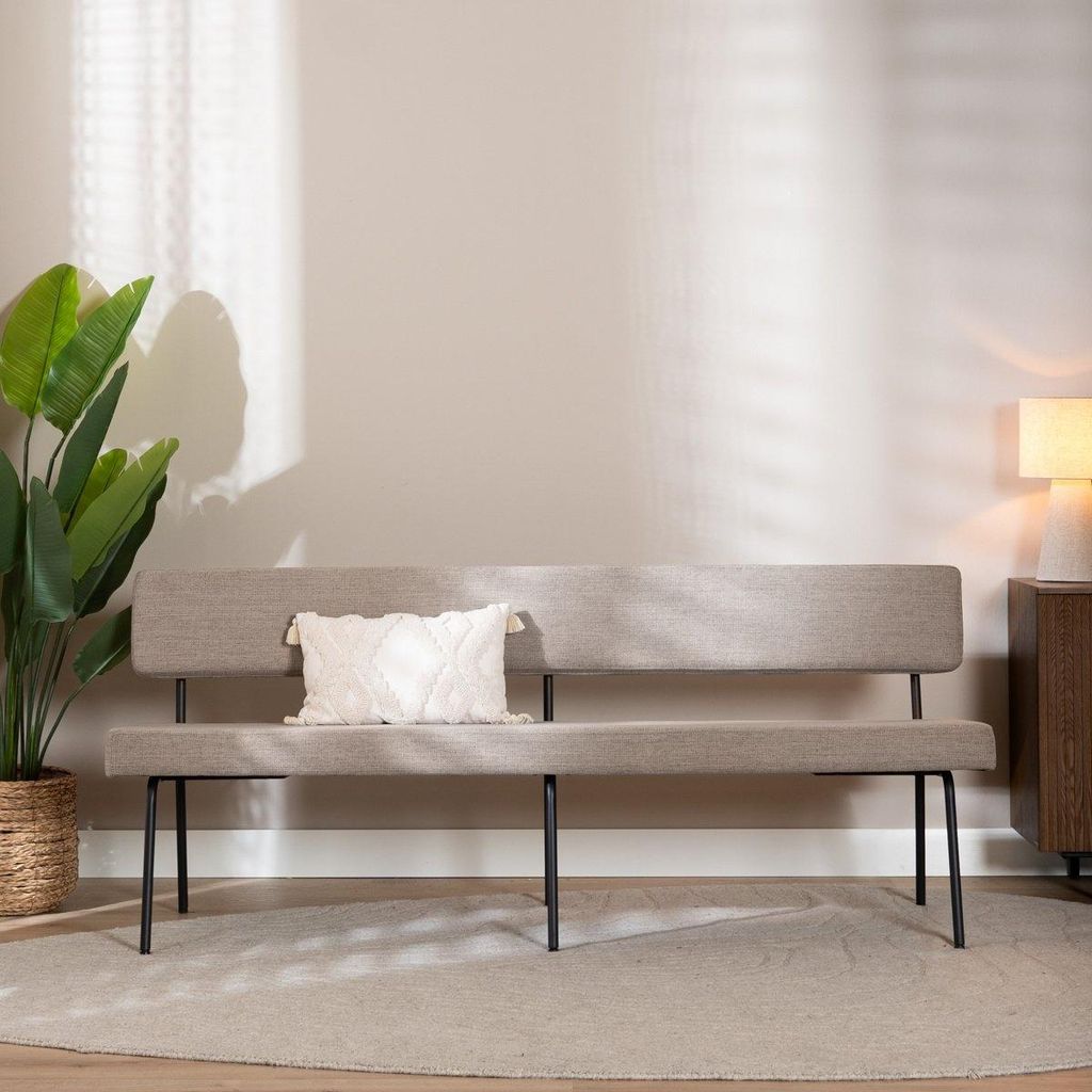 A bench in a room with a plant and a lamp.
