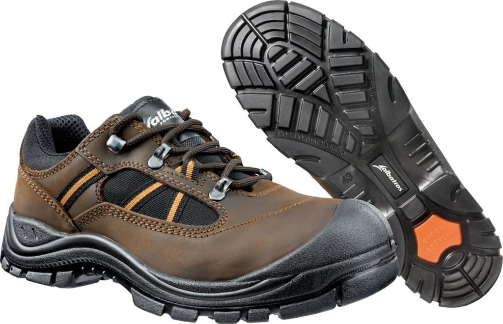 A pair of brown safety shoes with black and orange accents, shown from a slightly angled front view, with the sole of another shoe visible in the background.