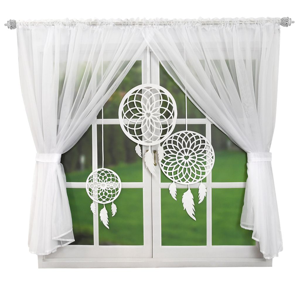 A window with white curtains and three white dreamcatchers hanging in front of it.