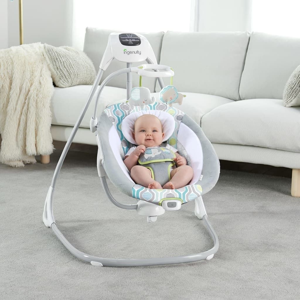 A baby is sitting in a baby swing in a living room.