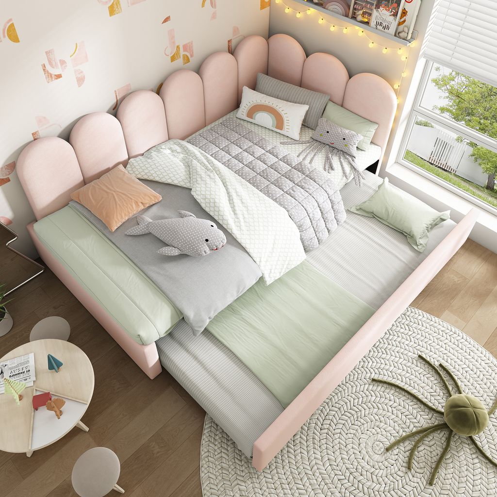 A child's bedroom with a pink upholstered bed, bedding, and a small round table.