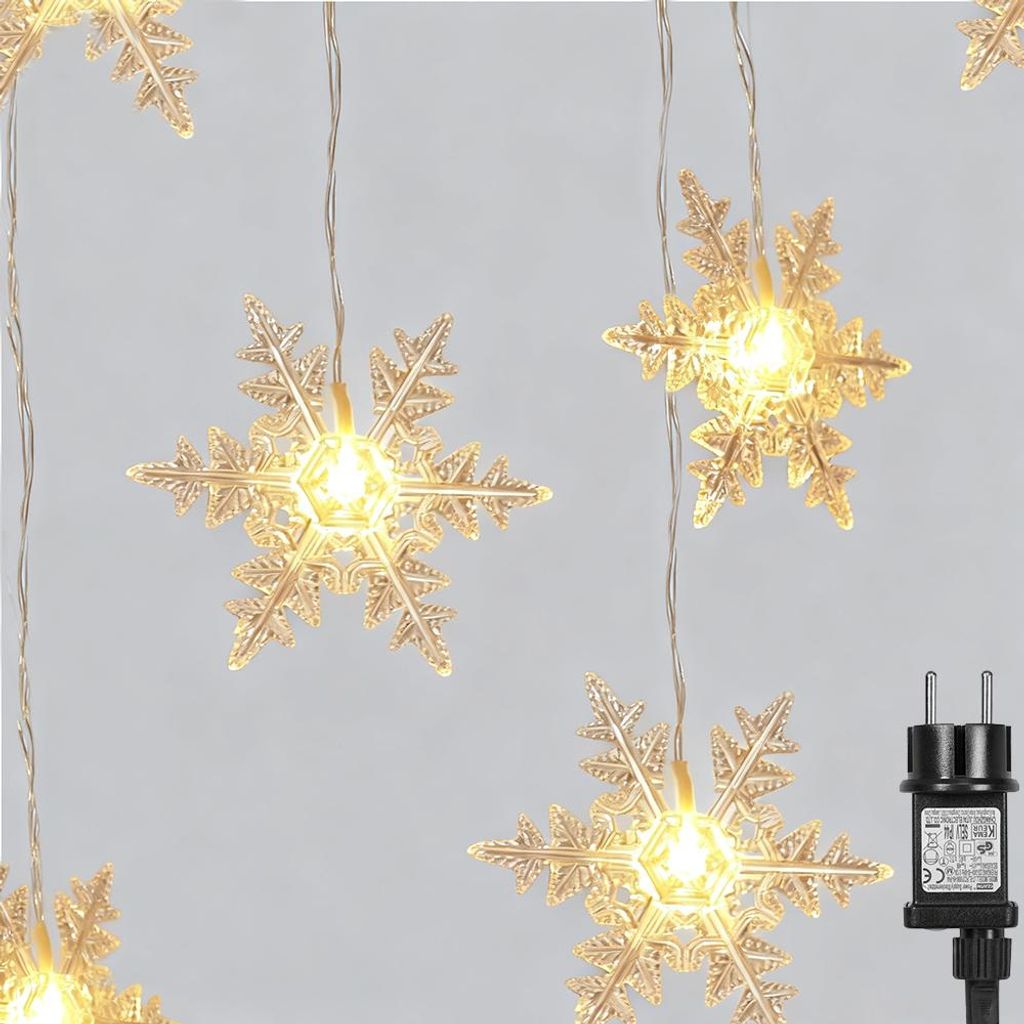 A string of snowflake-shaped LED lights hanging against a light gray background, with a power adapter visible on the right.