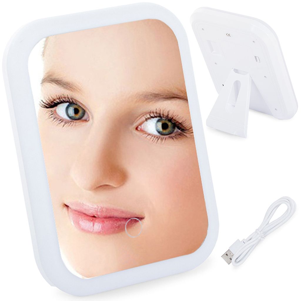 A close-up of a woman's face reflected in a cosmetic mirror, with the back of the mirror and a USB cable visible in the background.