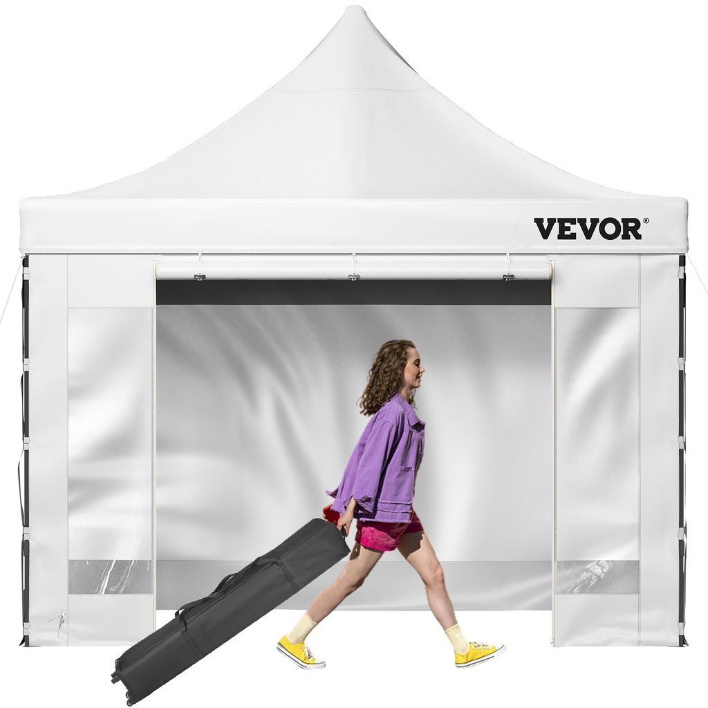 A woman walks past a white pop-up tent, pulling a black carrying bag with wheels.