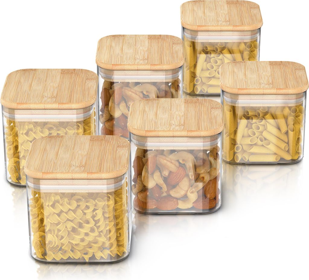 A set of six glass storage jars with bamboo lids, filled with different types of pasta and nuts, arranged on a white background.