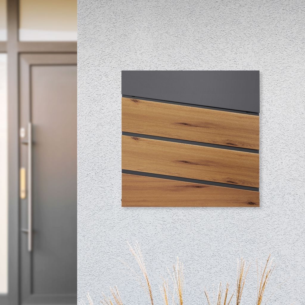 A mailbox with a wood-look front is mounted on a textured white wall next to a gray door.