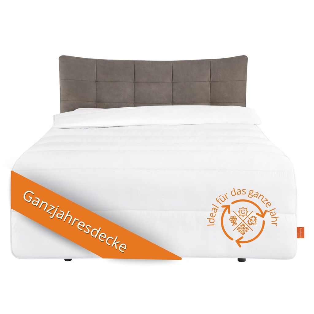 A white bed with a gray headboard, featuring a white duvet and an orange banner with text.