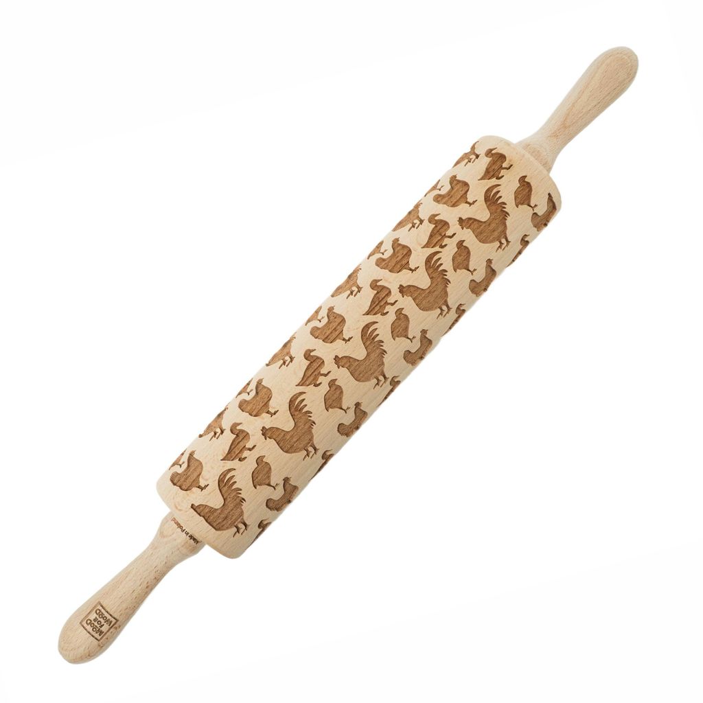 A wooden rolling pin with a chicken pattern engraved on it, placed on a white background.