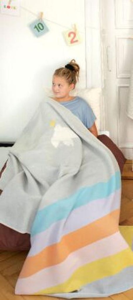 A young girl is wrapped in a colorful striped blanket.