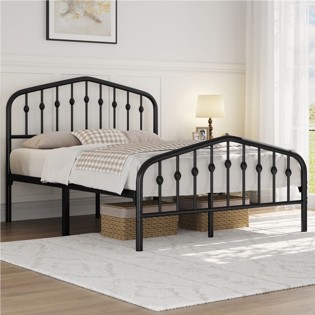 A black metal bed frame with a crown motif headboard is shown in a bedroom setting.