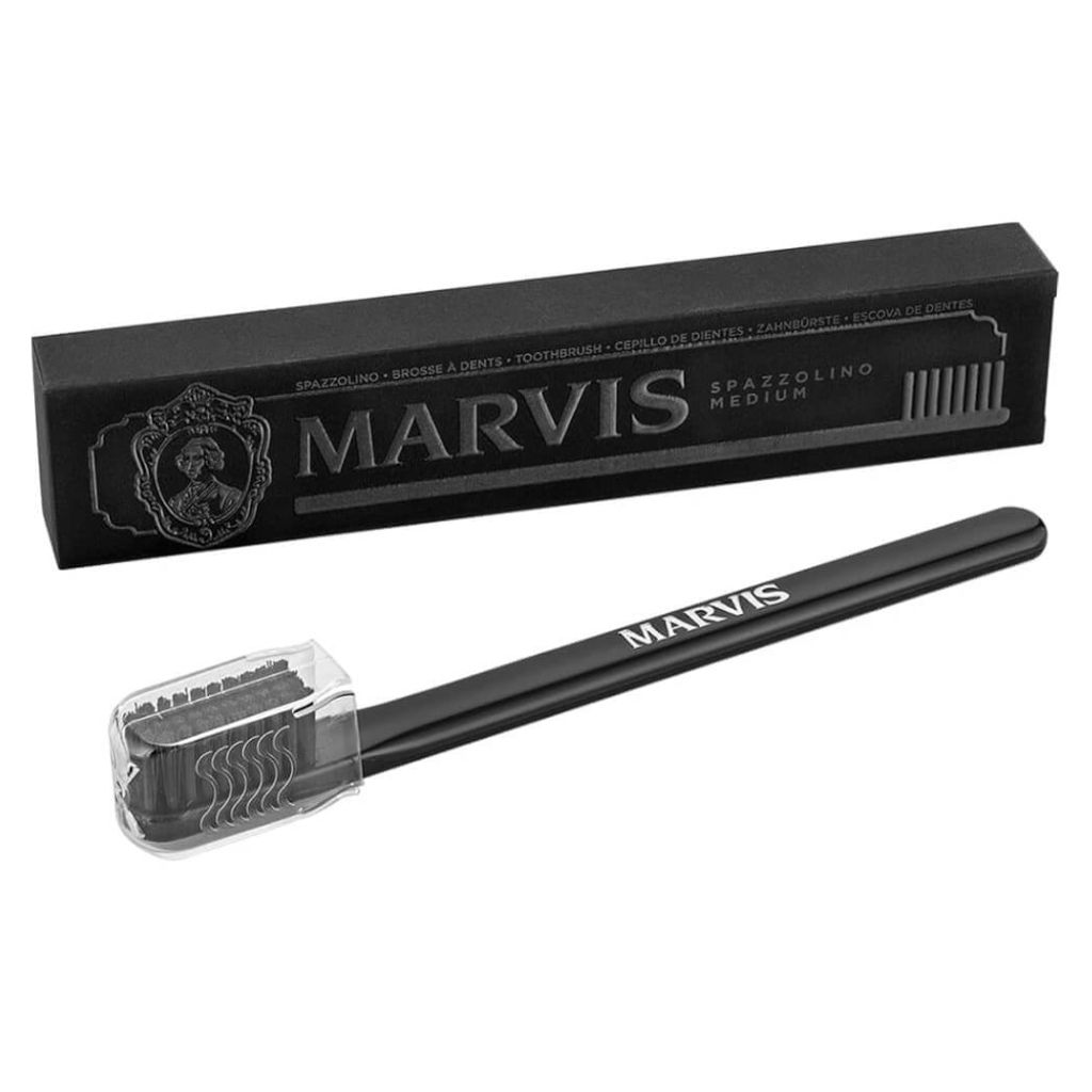 A black Marvis toothbrush with a clear protective cap and its black packaging box.