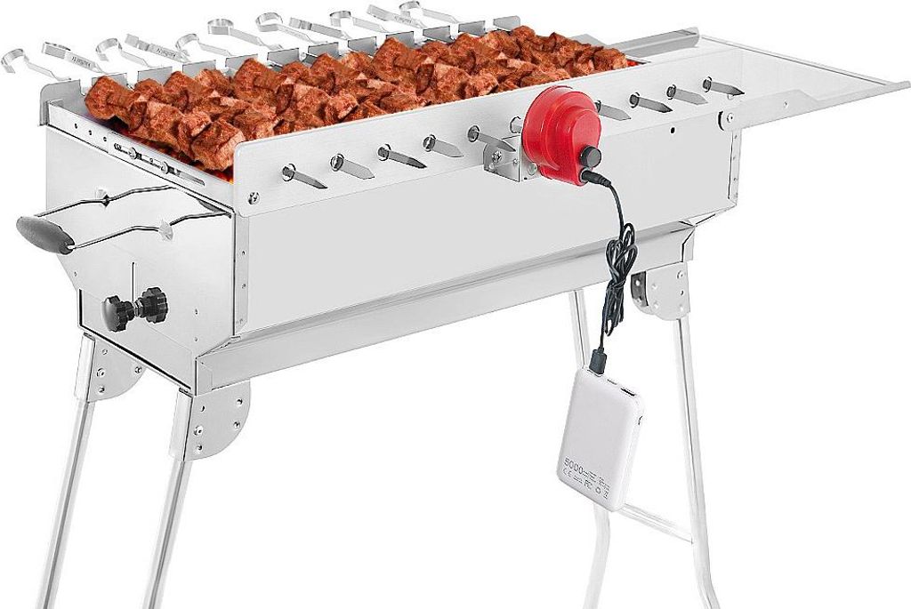 A stainless steel charcoal grill with skewers of meat, a red motor, and a white power bank.