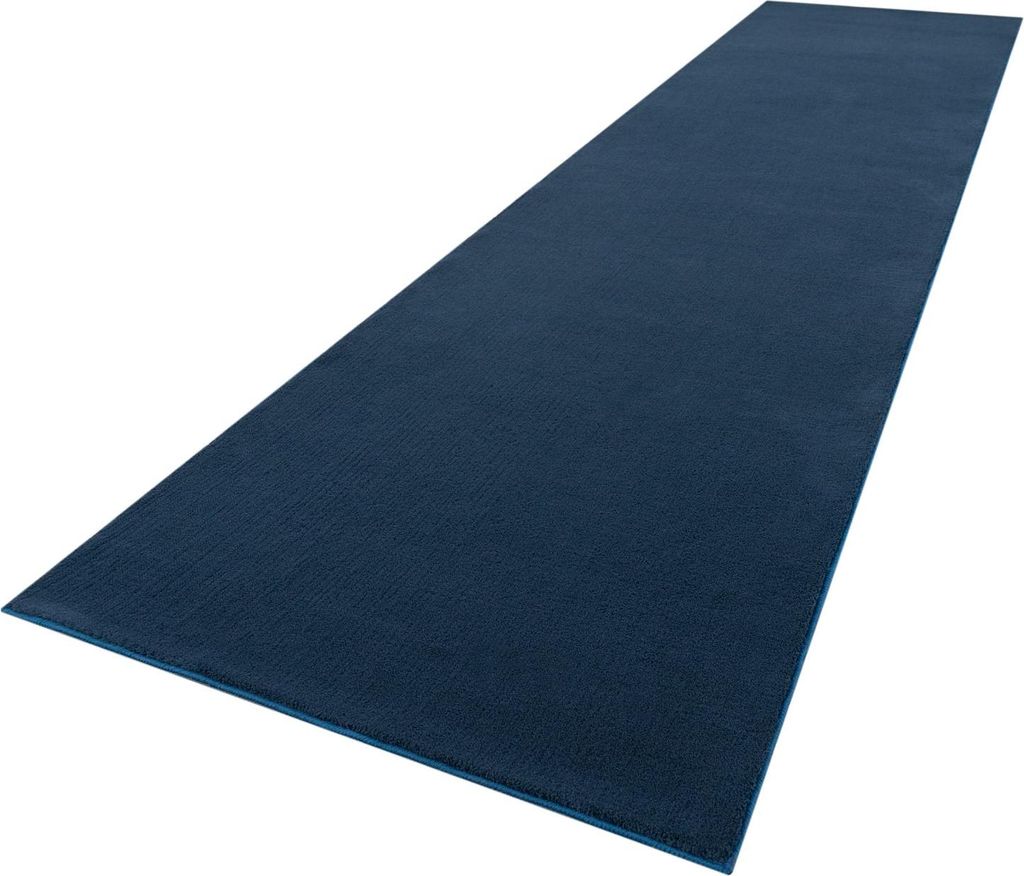 A long, dark blue runner rug is shown from a diagonal angle against a white background.