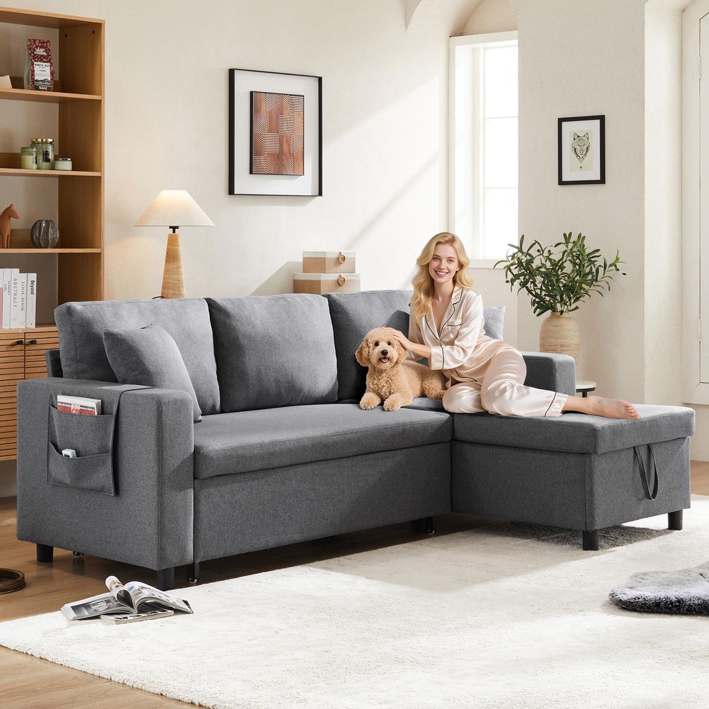 A woman and a dog are relaxing on a gray sectional sofa in a living room.