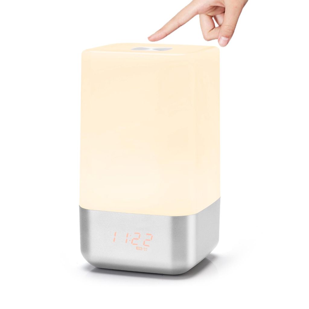 A hand is touching the top of a bedside lamp with a digital clock display.