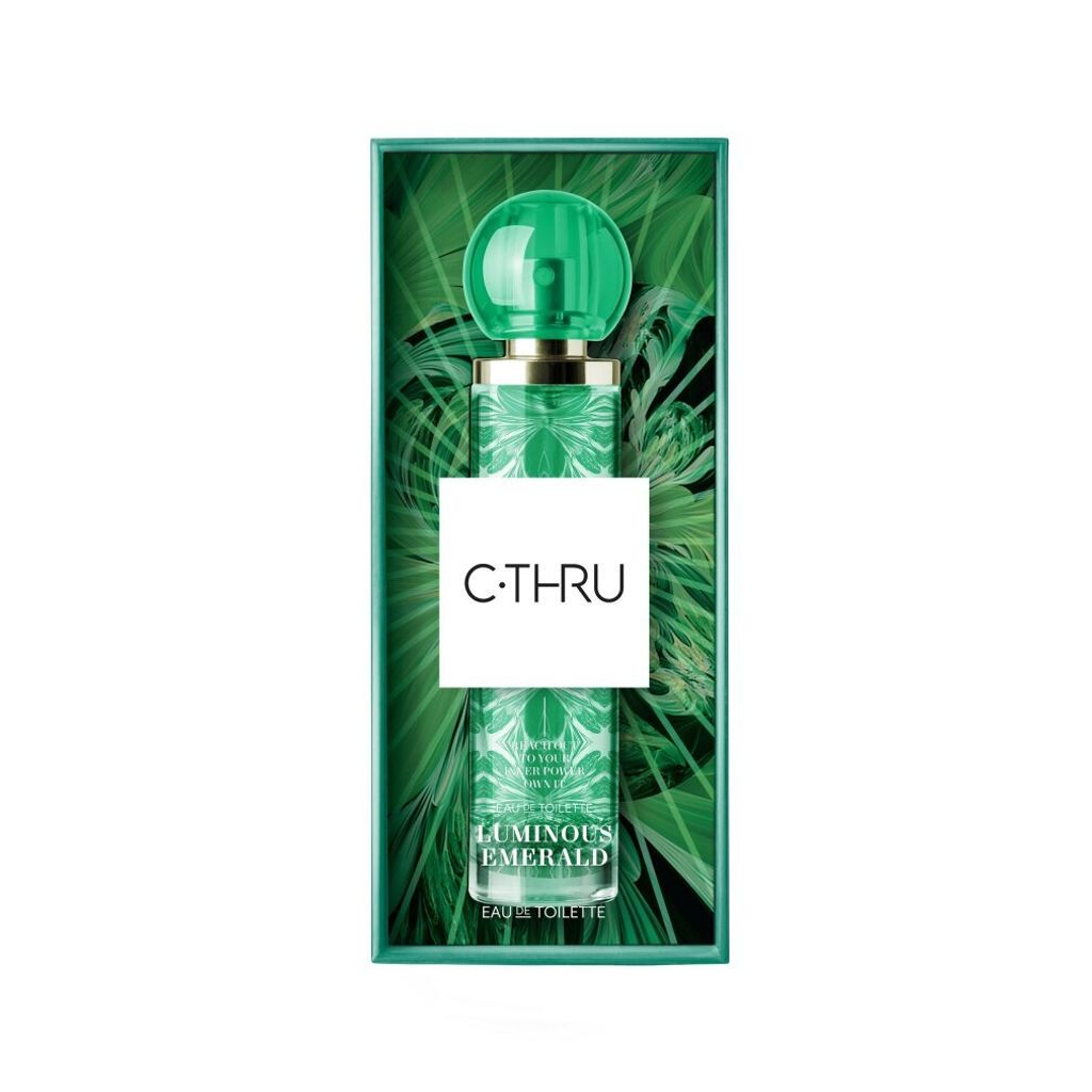 A bottle of C-Thru Luminous Emerald Eau De Toilette is presented in its packaging, which features a tropical leaf motif.