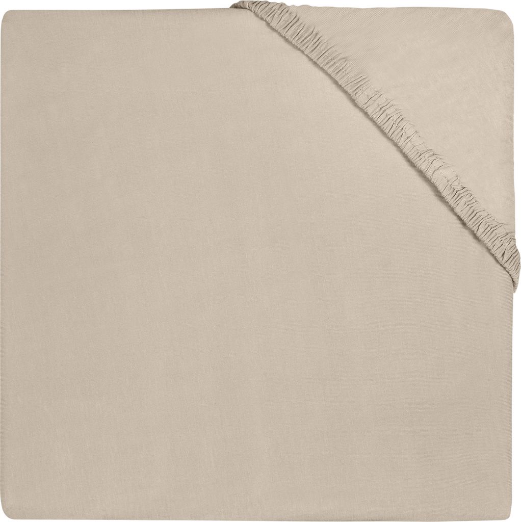 A close-up, top-down view of a beige fitted sheet with elastic gathering at one corner.
