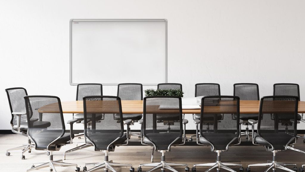 A meeting room with a whiteboard and chairs around a table.