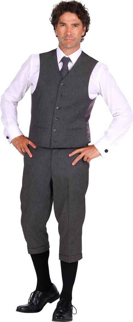 Ein Mann trägt ein komplettes Kostüm im 20er-Jahre-Stil mit grauer Weste, Knickerbockerhose, weißem Hemd, schwarzer Krawatte und schwarzen Schuhen.